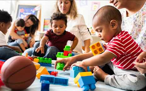 children playing blocks with childcare staff